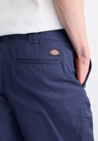 Pantaloni da lavoro blu navy con una superficie liscia, dotati di tasca posteriore, una patch con logo e un design a vestibilità regolare.