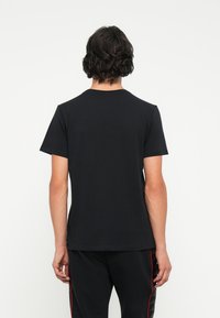 Czarny t-shirt z krótkim rękawem o klasycznym dekolcie, wykonany z miękkiej bawełny, o gładkiej fakturze i bez widocznych logo.
