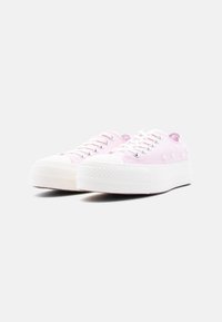 Ζευγάρι ροζ πάνινα sneakers χαμηλού ύφους με λευκές λαστιχένιες σόλες και κορδόνια, διακοσμημένα με μικρή κεντητική λουλουδιών στις πλευρές.