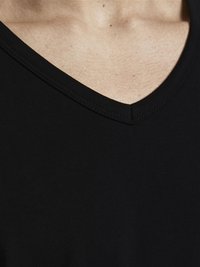 T-shirt noir à col en V fabriqué en coton doux, avec une texture lisse et une coupe ajustée, des bords finement cousus et un décolleté profond.