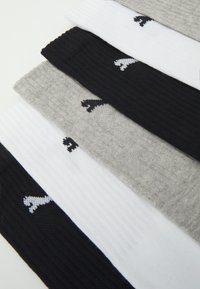 Fem par strumpor i svart, grått och vitt. Ribbade texturer med stickad design och en liten logotyp på varje par.
