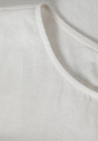 Linenový top s oválnym výstrihom, s jemnou bielou textúrou a subtilným vzorom tkania. Čisté okraje a minimalistický dizajn.