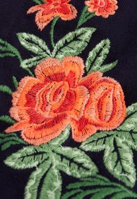 Broderad blommig design med orange rosor och gröna blad på en mörk marin bakgrund, som visar detaljerad utförande och textur.
