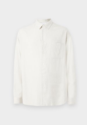 Vit långärmad skjorta med knappar och krage, en enda bröstficka och ett subtilt texturmönster på tyget.