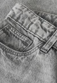 Siva traperska tkanina sa blagom teksturom, s malim prednjim džepom, kontrastnim šavovima i omčom za remen na vrhu.