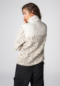 Beige- und graues Fleecefaser-Jacke mit Leopardenmuster, hohem Kragen und glattem Stoffoberteil. Enthält elastische Bündchen und eine lockere Passform.
