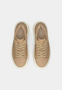 Béžové semišové tenisky se zavazováním na tkaničky, kulatou špičkou, texturovanou bílou gumovou podrážkou a prošitými detaily. Na stélce je viditelné logo značky.