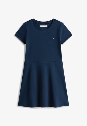 Navy blauwe katoenen jurk met korte mouwen, ronde halslijn, getailleerde bovenkant en uitlopende rok. Heeft een klein logo op de borst.