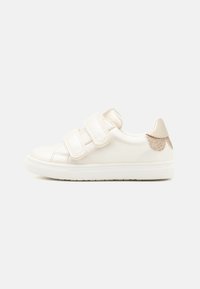 Basket en synthétique blanche avec deux sangles Velcro, un bout arrondi et un accent doré pailleté sur le talon. Semelle en caoutchouc texturé.