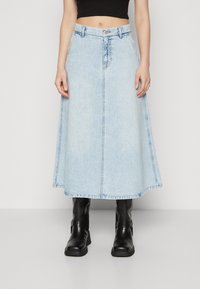 Lyseblå denimskjørt med tettsittende midje, utsvingt kant, og rå kanter. Kombinert med svarte lær ankelstøvler.