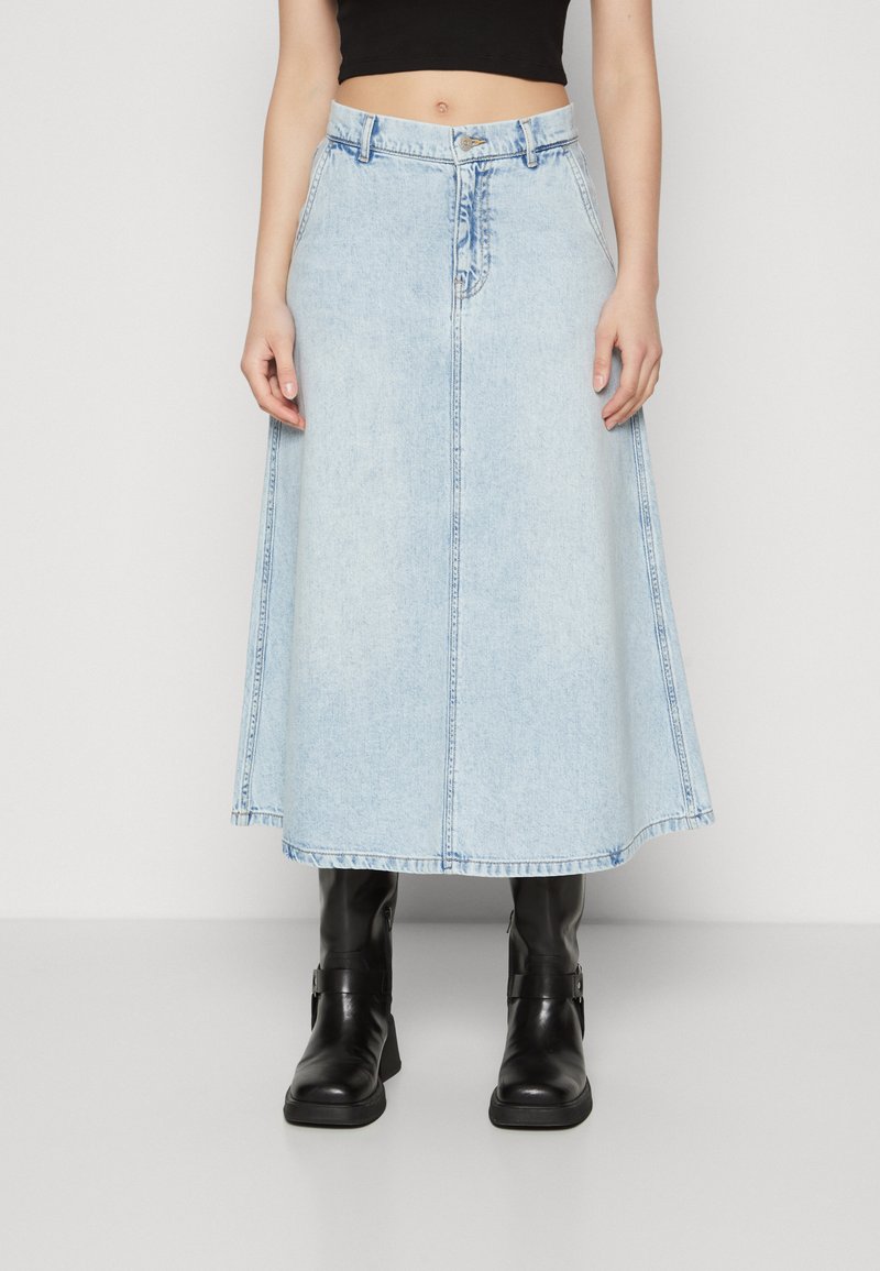 Lyseblå denimskjørt med tettsittende midje, utsvingt kant, og rå kanter. Kombinert med svarte lær ankelstøvler.