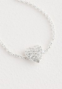 Silberarmband mit Herzanhänger, verziert mit klaren, funkelnden Strasssteinen. Strukturierte und glatte Oberflächen.