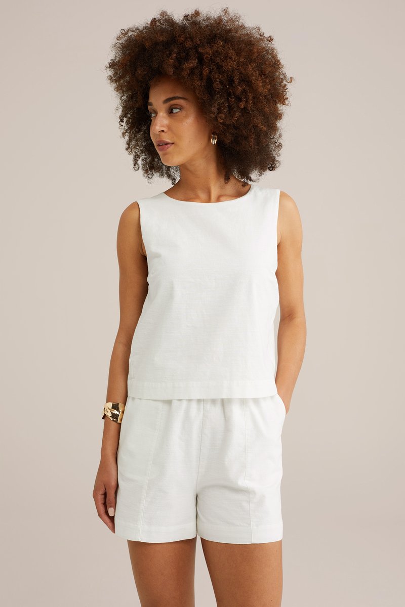 Vit linne utan ärmar med rundad halsringning, ihopsatt med matchande shorts. Tyget ser ut att vara lätt och mjukt. Minimalistisk design.