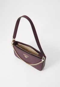 Sac à main en cuir bordeaux avec une texture en relief, quincaillerie dorée et une bandoulière décorative en chaîne. La fermeture éclair révèle un intérieur beige.