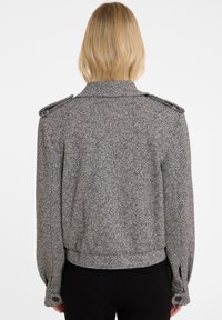 Grijze textuurjacket met schouderepauletten, een aangesloten taille en knoopmanchetten. Heeft een geweven patroon, ideaal om te lagen.