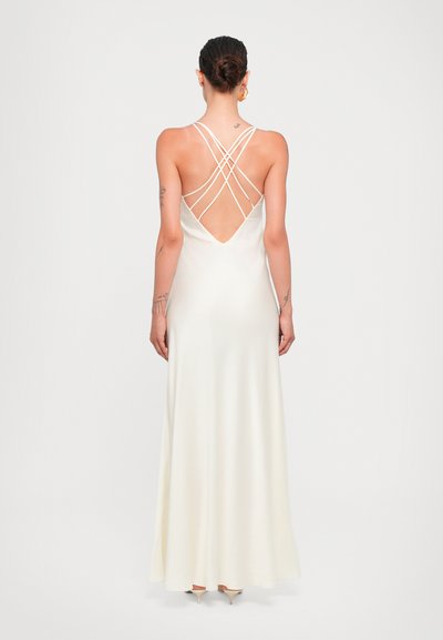 Robe longue en satin ivoire avec un dos en V profond, dotée de bretelles croisées. Jupe fluide qui descend jusqu'au sol. Texture lisse tout au long.