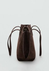Bolso tote de ante marrón con una textura suave, forma triangular, dos asas largas y parte superior abierta. Diseño minimalista sin hardware visible.