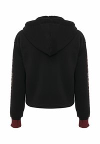 Zwarte cropped hoodie met capuchon, geribbelde bordeaux rode manchetten en grafische tekst langs de mouwen. Zachte stof met een gladde textuur.