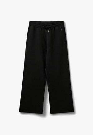 Pantaloni de trening negri, cu croi larg, dintr-un material moale; au o talie elastică cu șnur și buzunare laterale. Fără modele sau accente vizibile.