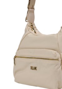 Borsa a spalla in tessuto beige con una tasca con zip dorata e logo. Presenta una superficie liscia e una tracolla regolabile. Forma arrotondata.