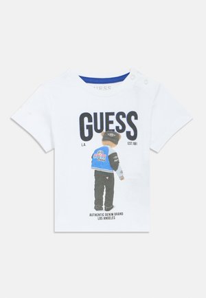 Wit katoenen t-shirt met een afbeelding van een beer in een blauw-zwarte jas en de tekst "GUESS" en "AUTHENTIC DENIM BRAND LOS ANGELES."