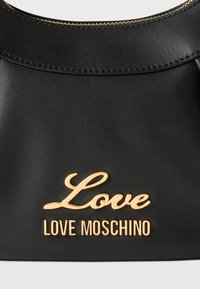 Μαύρη δερμάτινη τσάντα χειρός με χρυστό φερμουάρ και χρυσά γράμματα λογότυπου "Love Moschino" στο κέντρο μπροστά.