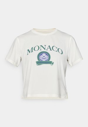 Fehér pamut póló zöld "MONACO" felirattal, kerek logó kék díszítésekkel, rövid ujjakkal és oldalhasítékos cropped fazonnal.