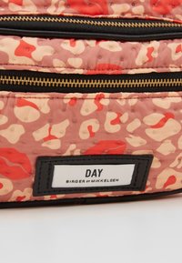 Zaino rosa trapuntato con un motivo astratto rosso e crema, dotato di cerniere nere e un'etichetta rettangolare con la scritta "DAY BIRGER ET MIKKELSEN."