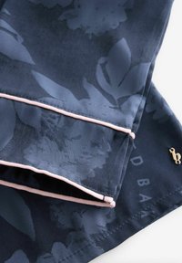 Floral-patterned navy fabric with a silky texture, featuring light pink piping and a small gold accent near the hem.