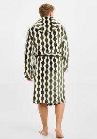 Hættebadekåbe med bølget mønster i olivengrøn og hvid, lavet af blødt materiale, med bindebånd i taljen og lange ærmer.