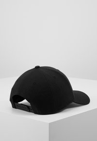 Svart bomull baseball cap med buet skjerm, justerbar snapback-lukking og seks ventilasjonshull på toppen.