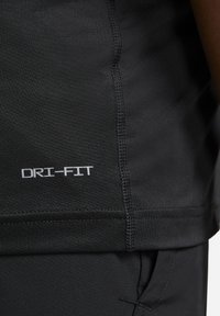 Camiseta atlética negra con una textura suave, mangas cortas y dobladillo cosido. Muestra el logo "DRI-FIT" en blanco cerca de la parte inferior.