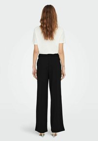 Sorte bukser med vide ben og høj talje, kombineret med en hvid, kortærmet top. Stoffet fremstår glat med en skræddersyet pasform.