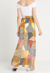 Gonna maxi con un design a patchwork caratterizzato da motivi floreali in arancione, giallo, rosa e nero. Realizzata in tessuto leggero, lunghezza fino alla caviglia.