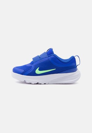 Μπλε αθλητικό παπούτσι με πράσινο λογότυπο Nike, ιμάντες βέλκρο και λευκή σόλα, εμφανιζόμενο από το πλάι σε απλό φόντο.