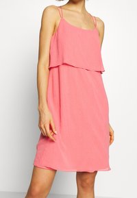 Rosa ärmelloses Kleid mit geschichtetem Design, aus weichem, strukturiertem Stoff. Verstellbare Träger und lockere Passform für Komfort.