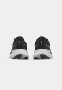 Black athletic shoes with gray accents, featuring a textured upper, cushioned sole, and reflective hardware. Rear view showing eyelets and branding.