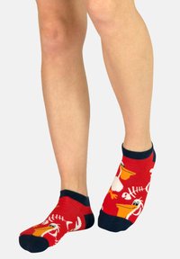 Rote Knöchelsocken mit einem verspielten Design von Pelikanen und Fischgräten, mit navyblauen Bündchen und Zehen, aus einem weichen, dehnbaren Material.