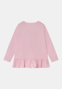 Top rosa a maniche lunghe con collo tondo e orlo a volant. Realizzato in tessuto morbido con una texture uniforme, privo di motivi o hardware visibili.