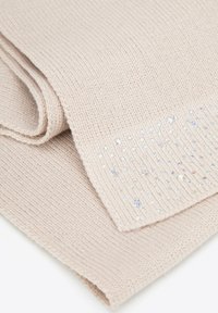 Écharpe beige tricotée avec un motif texturé, ornée de cristaux clairs et brillants sur un bord pour un intérêt visuel.