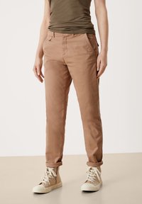 Ljusbruna chinos med slim passform, med sidelommer, uppvikta fållar och subtil textur. Matchas med beige hög-top sneakers.