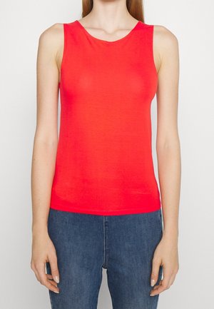 Top rosso senza maniche realizzato in un tessuto liscio, con scollatura rotonda e forma aderente. Abbinato a jeans in denim blu.