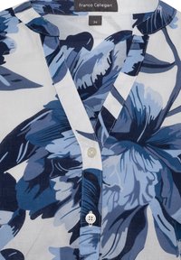 Blumenbluse in Blau- und Weißtönen, mit V-Ausschnitt, Knopfverschluss und einem glatten Stoff mit glänzendem Finish.