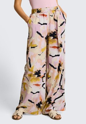 Pantalon à jambes larges avec motif abstrait de coups de pinceau rose, jaune, noir et orange, taille nouée, poches latérales, porté avec des sandales beige à enfiler.