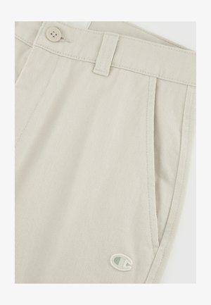 Beżowe szorty z mieszanki bawełny z teksturowaną powierzchnią, z zapięciem na guzik, szlufkami na pasek oraz małą naszywką logo z boku.