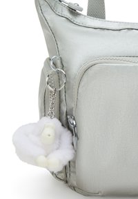 Silver metallic shoulder bag with textured finish, featuring a front pocket and keychain attachment with a fluffy white ape figure.