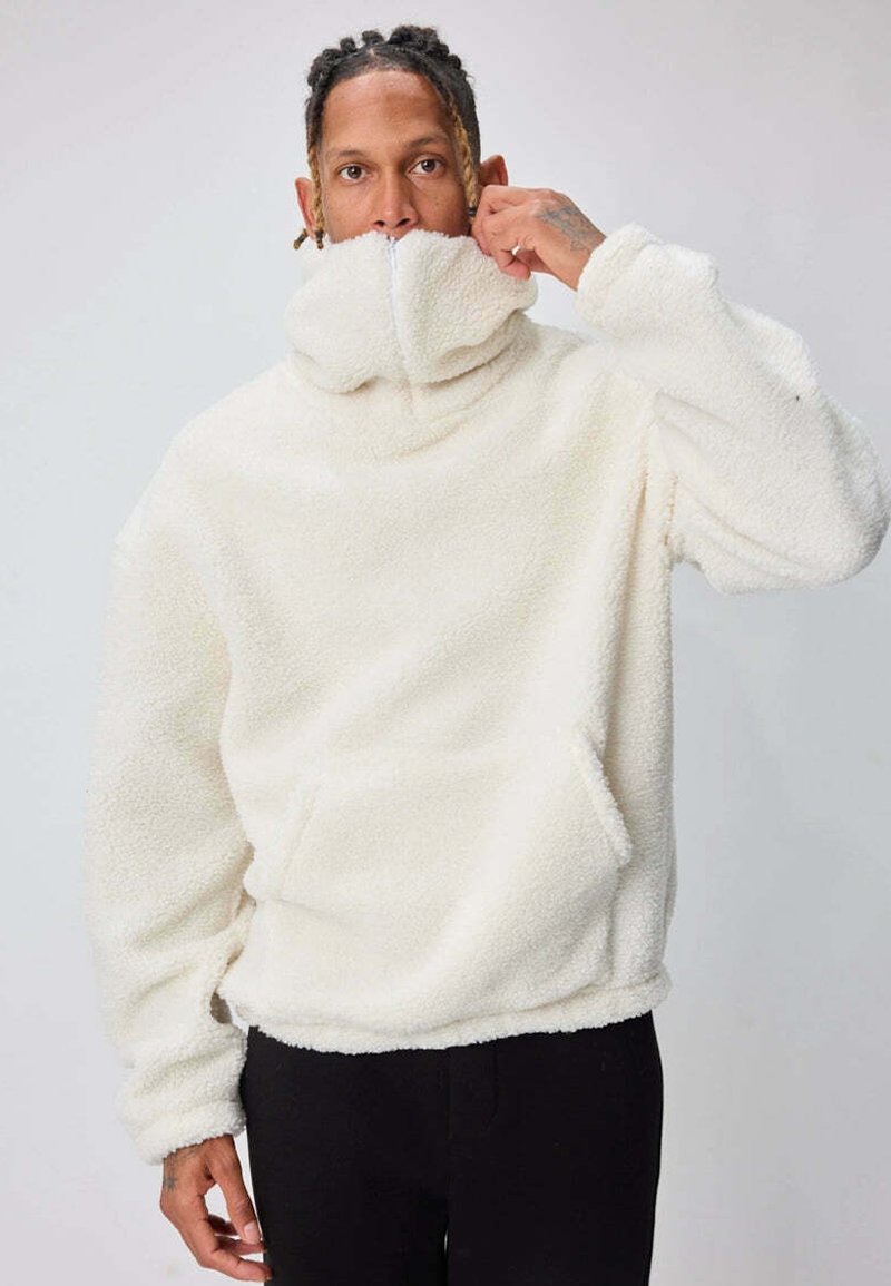 Pull-over en polaire blanche avec col montant, fermeture éclair mi-longue, poche kangourou et poignets côtelés. Texture douce, coupe décontractée.