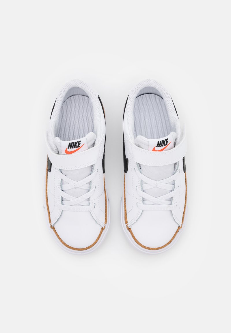 Zapatillas blancas de Nike con un swoosh negro, suela de goma y una correa de Velcro. El zapato tiene una superficie texturizada y cordones para un ajuste seguro.
