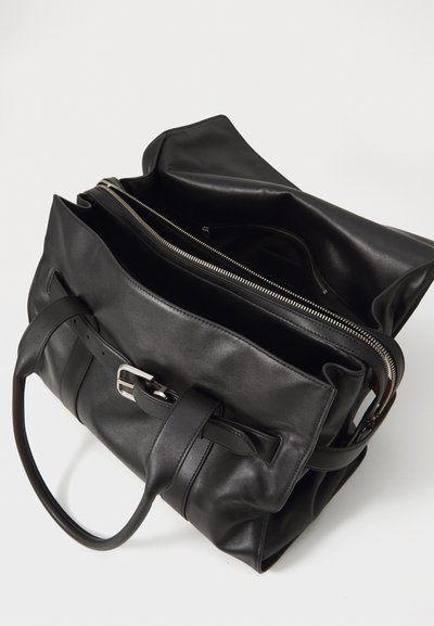 Borsa in pelle nera con finitura testurizzata, dotata di due manici, un dettaglio con fibbia e un ampio scomparto con zip. Interno visibile.