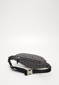 Piccolo marsupio Calvin Klein con motivo a logo CK bianco e nero, tasca frontale con zip e tracolla nera regolabile con fibbia in metallo argentato.